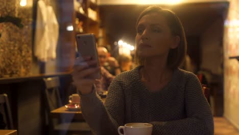 Junge-Frau-im-Chat-auf-Smartphone,-sitzen-in-gemütlichen-Kaffeehaus,-kostenloses-wi-fi