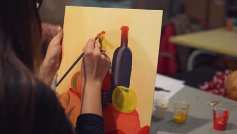 Young-woman-artist-is-painting-picture-on-canvas-in-art-studio