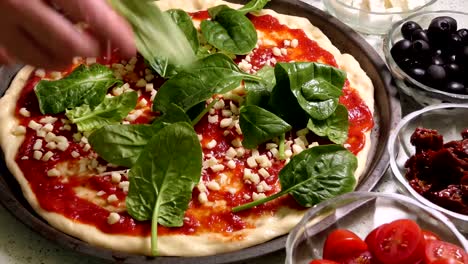 Pizza-Topping-vorbereiten.-Verlegung-von-frischem-Spinat-lässt-auf-Pizza-Topping.