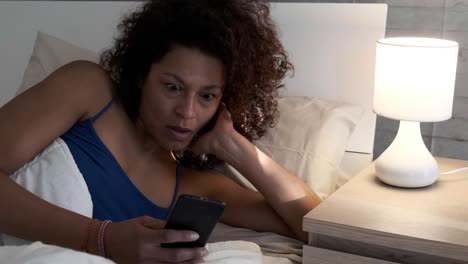 Un-texto-de-mujer-negra-en-el-teléfono-móvil-en-la-cama