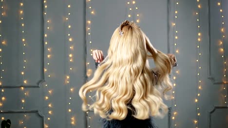 Una-mujer-rubia-en-un-hermoso-vestido-y-una-corona-se-presenta-en-el-estudio.-Sofá-rojo