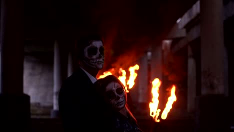 Couple-with-skull-make-up-on-the-background-of-burning-fire-and-smoke.-Halloween