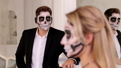 Una-chica-con-un-maquillaje-terrible-para-Halloween,-en-el-fondo-es-un-hombre-en-un-traje.