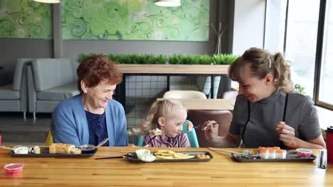 Mama-und-Großmutter-füttern-das-kleine-Mädchen-zusammen.