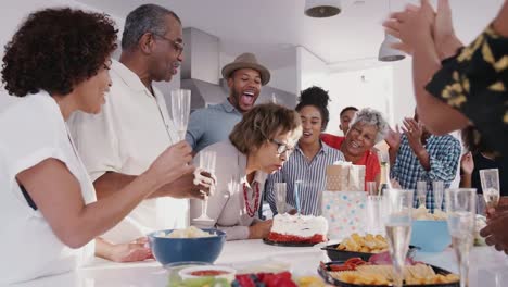 La-anciana-mujer-negra-soplando-la-vela-en-el-pastel-de-cumpleaños-durante-una-celebración-con-su-familia