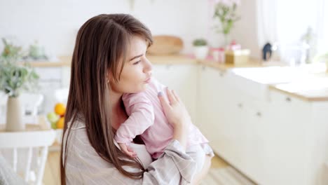 Cuidando-a-la-joven-madre-calmante,-besando-y-acariciando-a-su-linda-hijita-llorando-amargamente-en-sus-brazos-en-casa