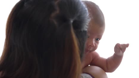 4K-Rear-view-close-up-shot-of-young-adult-asian-woman-mother-standing-near-window-in-home-bedroom-and-holding-her-newborn-baby-girl-daughter-on-shoulder.-Mother-day-and-baby-health-care-concept.