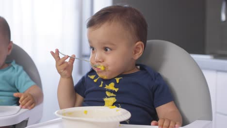 Mellizos-Asiáticos-Desordenados-Comer-Baby-Puree-con-Cucharas