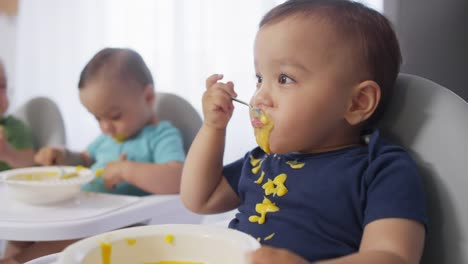 Trillizos-Asiáticos-descuidados-en-altas-sillas-comiendo-puré