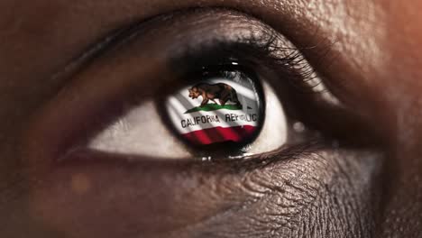 Woman-black-eye-in-close-up-with-the-flag-of-California-state-in-iris,-united-states-of-america-with-wind-motion.-video-concept