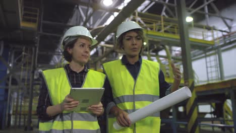 Two-Female-Engineers-Walking-through-Factory-and-Talking