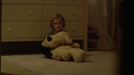 Niña-triste-se-sienta-en-su-piso-del-dormitorio-solo-con-un-animal-de-peluche