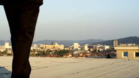 Depressive-businessman-walking-towards-the-edge-of-a-skyscraper-and-looking-down