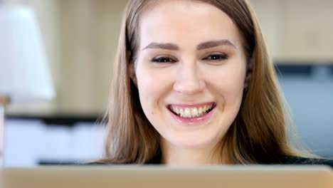 Frau-lächelnd-in-Richtung-Kamera-während-der-Arbeit-am-Laptop