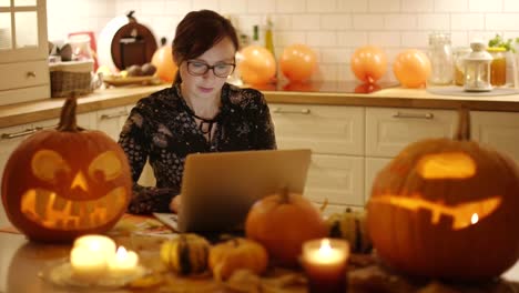 Frau-mit-Laptop-in-der-Nähe-von-Halloween-Dekorationen