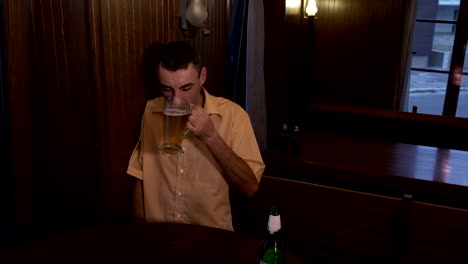 Drunk-guy-sitting-at-a-table-in-a-pub-and-drinking-beer