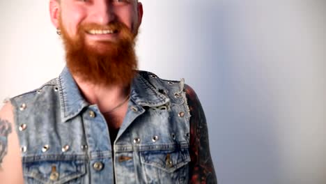 modern-youth.-a-cheerful-portrait-of-a-kindly-laughing-biker-with-tattoos-and-a-stylish-beard-and-mustache-in-a-denim-vest.