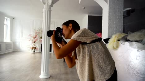 Young-charming-Woman-photographer-taking-photos-with-dslr-camera-indoors-with-grunge-interior-room