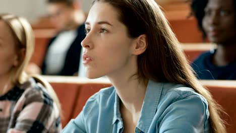 Beautiful-and-Intelligent-Young-Girl-Listens-to-a-Lecture-in-a-Classroom-Full-of-Multi-Ethnic-Students.-Shallow-Depth-of-Field.