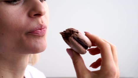 Close-up-of-caucasian-woman-biting-colorful-macaroons-on-white-background