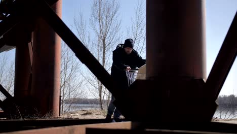 Obdachloser-Wallking-schieben-Karren-unter-Brücke