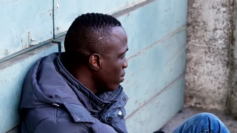 Sad-lonely-young-black-migrant-sit-in-the-street