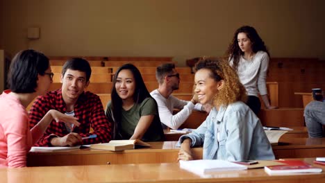 Sorglose-Mädchen-und-jungen-reden-und-lachen-sitzen-am-Schreibtisch-im-Hörsaal,-Studenten-sind-entspannend-während-der-Pause.-Gespräch,-moderne-Bildung-und-Jugendkonzept.