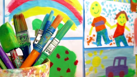 Paint-Brushes-In-Classroom-With-Paintings-On-Wall