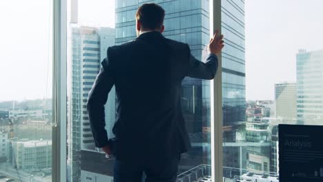 Nachdenklich-Geschäftsmann-tragen-Anzug-steht-in-seinem-Büro,-Blick-aus-dem-Fenster-und-Kontemplation-nächsten-Big-Business-Vertrag.-Wichtigsten-Geschäftsviertel-mit-Panorama-Fenster-Ansicht.-Gesättigte-Farben.