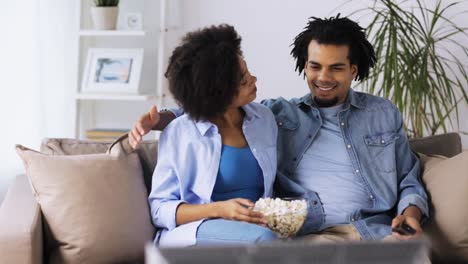 lächelnde-Paar-mit-Popcorn-zu-Hause-vor-dem-Fernseher