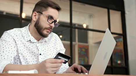 Man-paying-online-by-bank-card-at-laptop