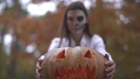 Víspera-de-Todos-los-Santos.-Chica-con-un-maquillaje-de-Halloween-de-miedo-con-una-calabaza-en-las-manos