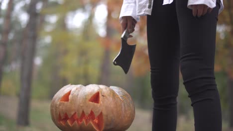 Víspera-de-Todos-los-Santos.-Una-chica-con-un-cuchillo-está-de-pie-sobre-una-calabaza-de-Halloween.