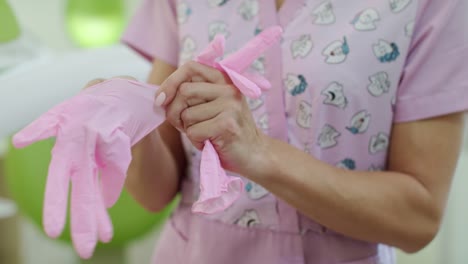 Mujer-enfermera-poner-en-los-guantes-de-la-salud.-Trabajador-de-asistencia-sanitaria-póngase-guantes-médicos