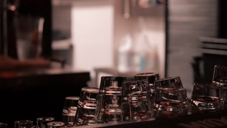 Colorful-light-reflecting-off-shot-glasses-as-bartenders-leave-kitchen