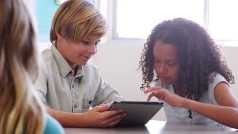 Dos-alumnos-con-tablet-PC-juntos-en-lección-de-escuela