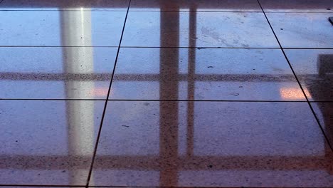 Floor-reflection-of-man-walking-with-carry-on-luggage-at-airport-terminal