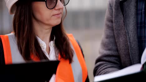 Engineer-communicates-and-demonstrates-the-construction-site-of-the-two-women-inspectors,-close-up