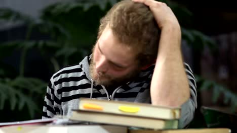 A-college-student-sits-at-his-desk-with-books-in-front-of-him