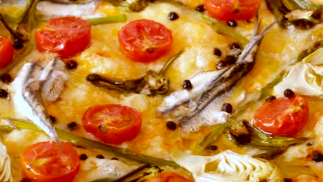 Pizza-with-anchovies,-artichokes,-cheese-and-sun-dried-tomatoes