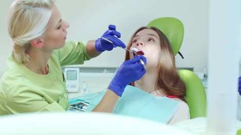 Especialista-en-Estomatología-trabajo-con-paciente-en-clínica-dental.-Dentista-mujer