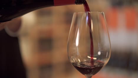 Slow-pouring-red-wine-into-a-wine-glass.-Female-hand-pours-wine-into-a-wine-glass-close-up.