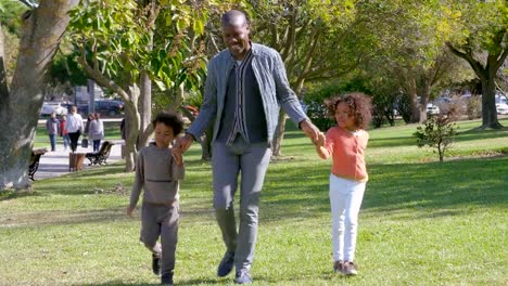 Glückliche-afroamerikanischen-Vater-Hand-in-Hand-mit-Kindern