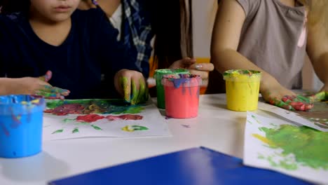 Multi-ethnic-little-girls-finger-painting-at-class