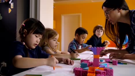 Niños-lindos-dibujo-con-el-profesor-en-clase-de-preescolar