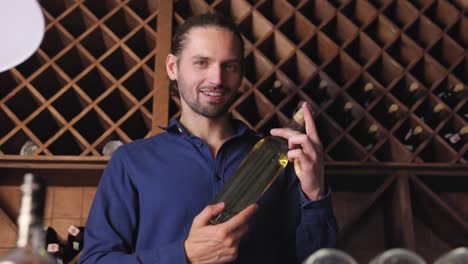 Smiling-Man-With-Bottle-Of-Wine-In-Cellar-At-Winery-Restaurant