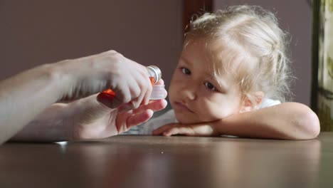 Mutter-Gießen-Medizin-Sirup-in-Messbecher-für-das-kranke-Kind.