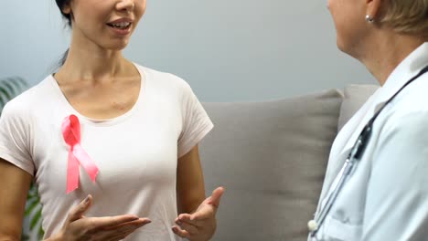 Woman-with-pink-ribbon-at-doctor-checkup,-breast-cancer-awareness,-prevention