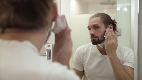 Man-Applying-Shaving-Foam-On-Face-Skin-And-Looking-In-Mirror