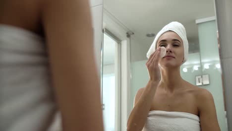 Pflege-der-Haut.-Frau-Gesicht-mit-Lotion-im-Badezimmer-reinigen